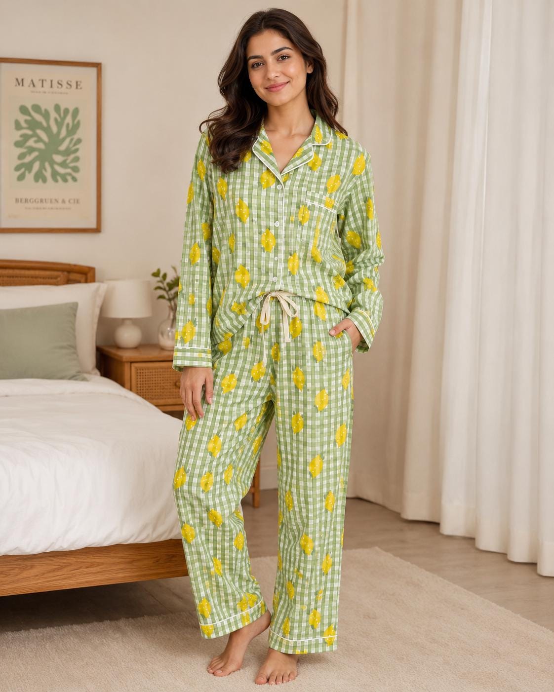 May include: A two-piece pajama set featuring a long-sleeved button-down shirt with a notched collar and matching full-length pants. The fabric is a light green and white gingham check pattern decorated with a repeating yellow lemon print.